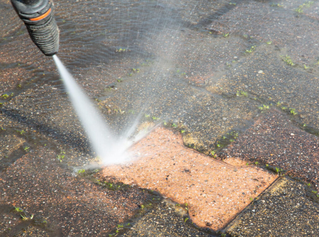 pressure washer cleaning a paver brick